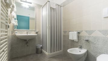Un baño con ducha, lavamanos y bidé.