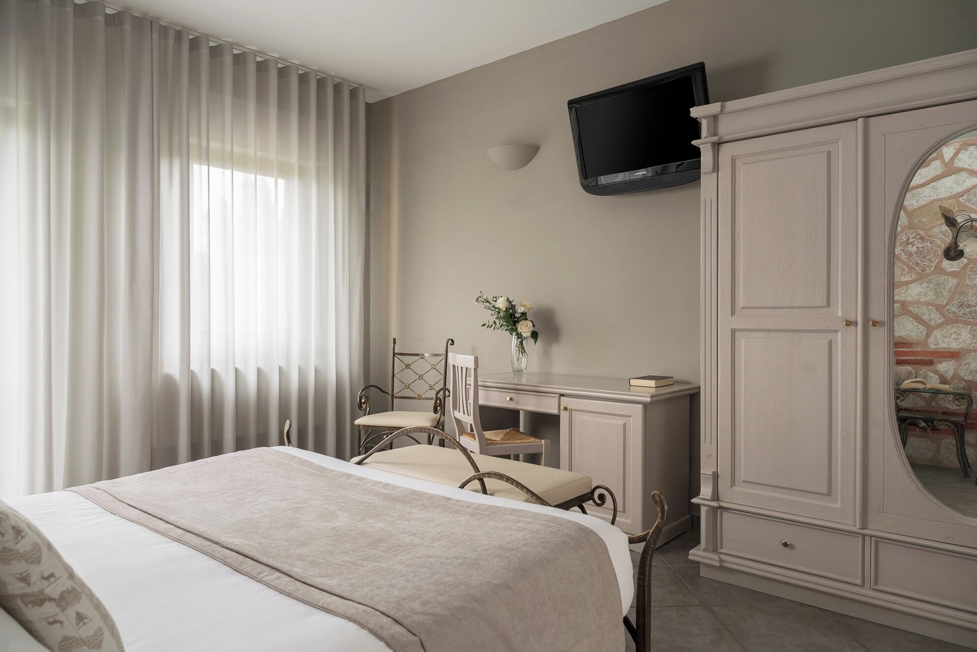 A bedroom with a bed, a desk, a chair, a TV, and a wardrobe.