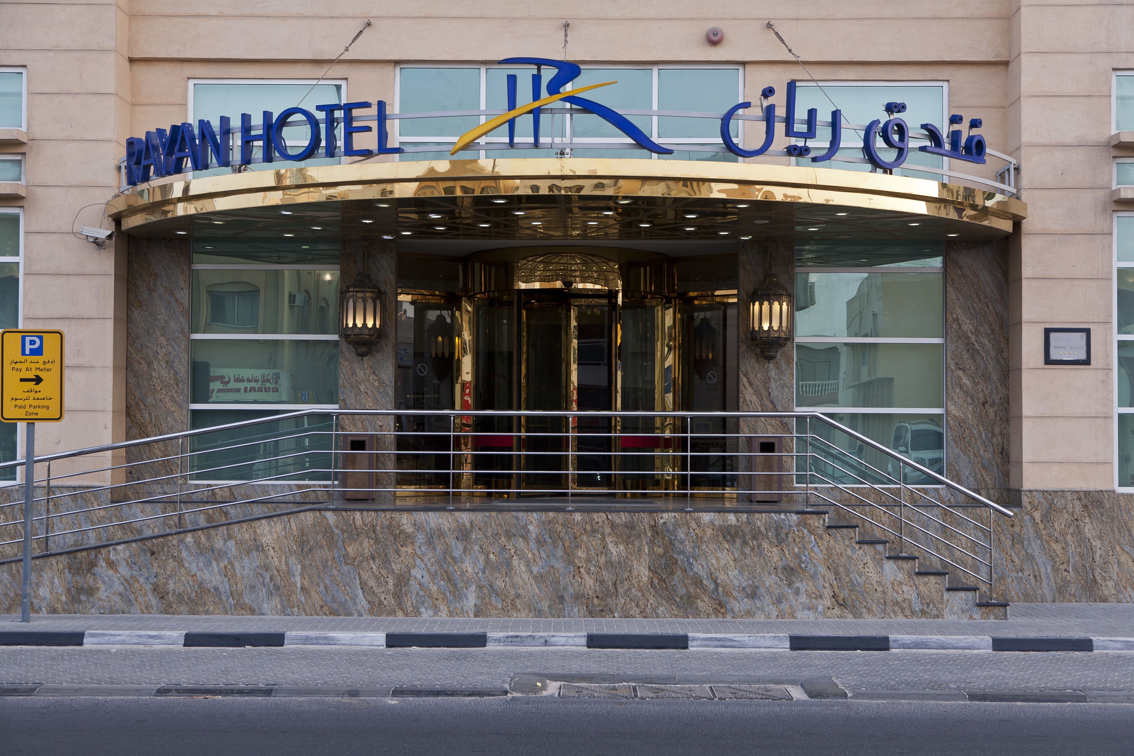 The exterior of Rayan Hotel with a marble facade, a prominent entrance with glass doors, and a staircase leading to the entrance.