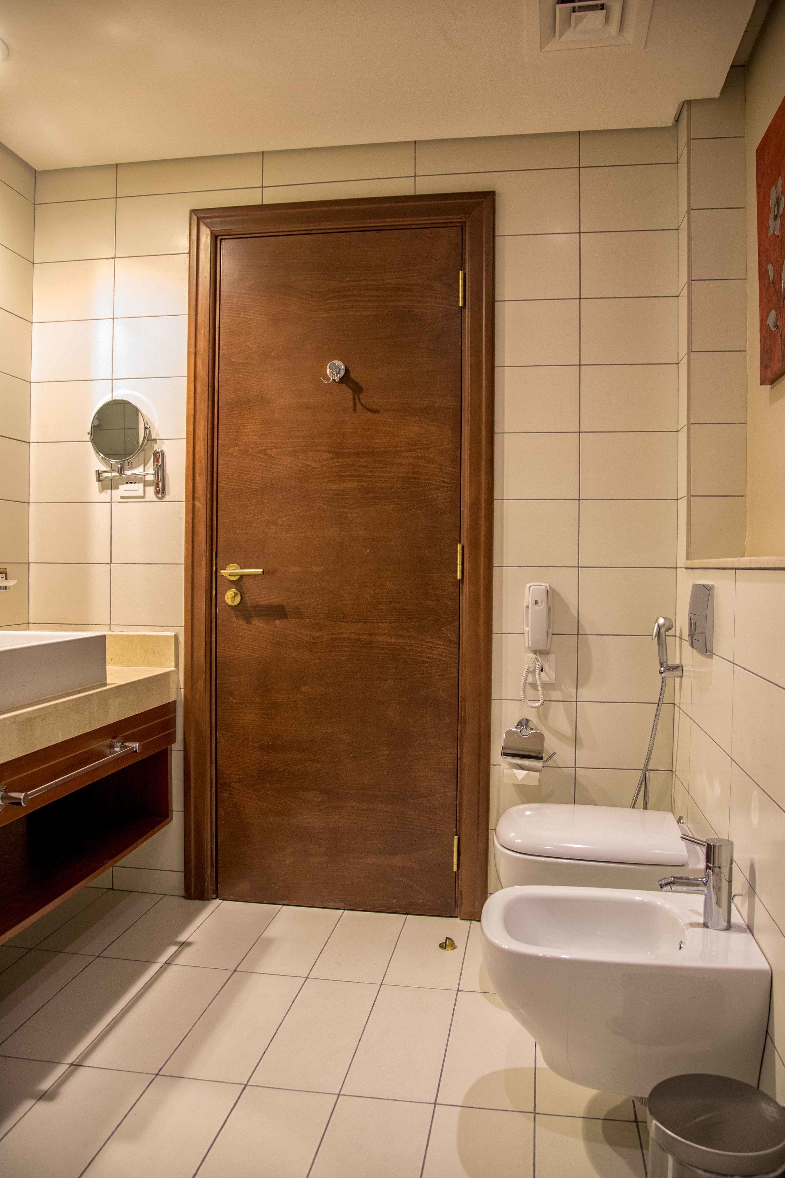 Un baño con puerta de madera, un lavabo, un bidé y un espejo.