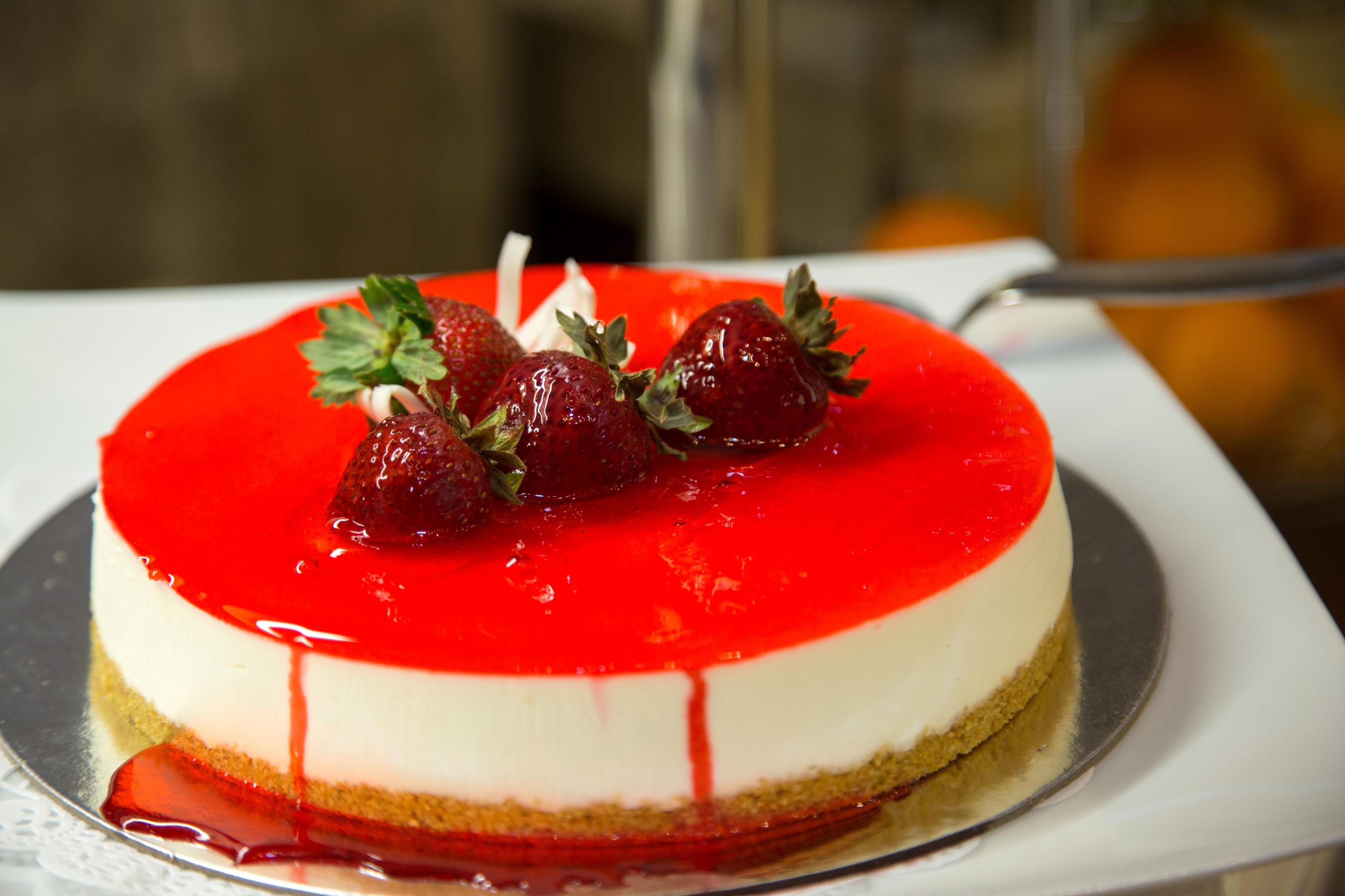 Un postre redondo con cobertura roja y fresas por encima.