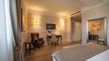 A hotel room with a bed, a desk with a chair, a television, and a door leading to another room.
