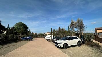 A parking area with several cars, including a white SUV, and a clear blue sky.