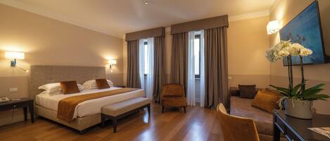 Une chambre d’hôtel avec un grand lit, une chaise, un bureau et une plante en pot.