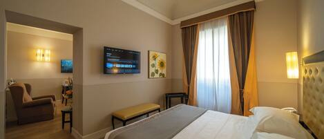 Habitación de hotel con cama, escritorio, silla, televisor y un cuadro en la pared.
