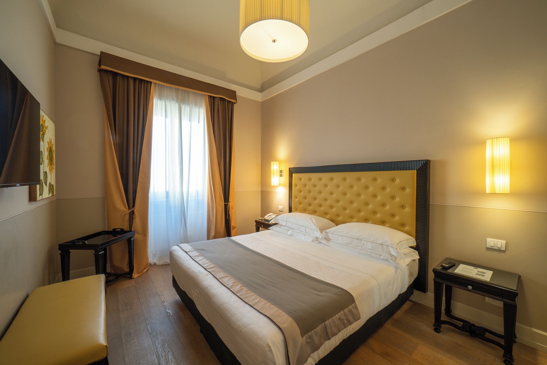 Ein Hotelzimmer mit einem großen Bett, einem Nachttisch, einer Lampe und einem Bild an der Wand.