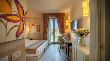 A hotel room with a bed, desk, chair, and a view of a pool and buildings.