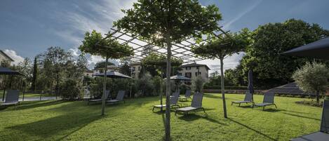 A well-maintained outdoor area with a pergola, several lounge chairs, and umbrellas.