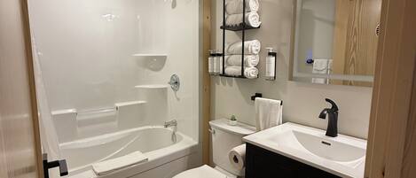 Un baño moderno con bañera, inodoro, lavabo y espejo.