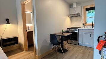 Una cocina compacta con electrodomésticos modernos, un comedor con mesa y sillas, y un extintor a la vista.