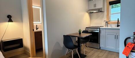 A compact kitchen with modern appliances, a dining area with a table and chairs, and a visible fire extinguisher.