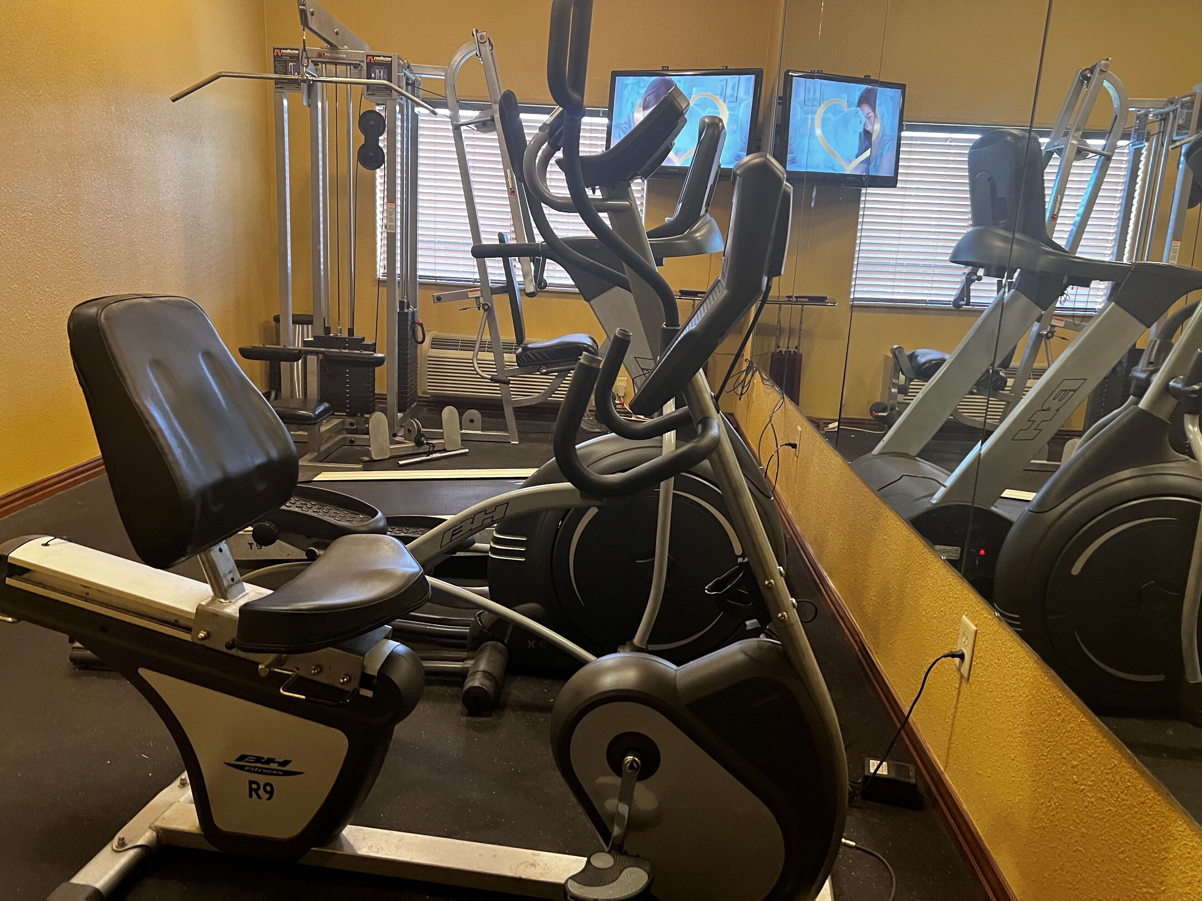 Una palestra con attrezzature cardio, macchine per pesi e cyclette.