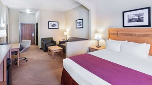 Quarto de hotel com cama, escrivaninha, cadeira e duas mesas de cabeceira com luminárias.