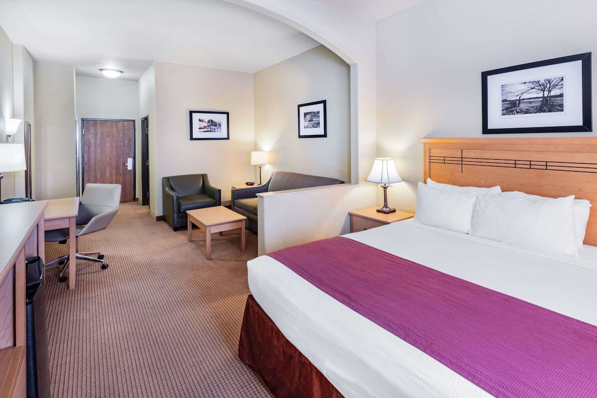 Une chambre d’hôtel comprenant un lit, un bureau, une chaise et deux tables de chevet avec des lampes.