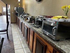 Montaje de bufé con varias estaciones de comida, incluyendo un horno tostador y un microondas.