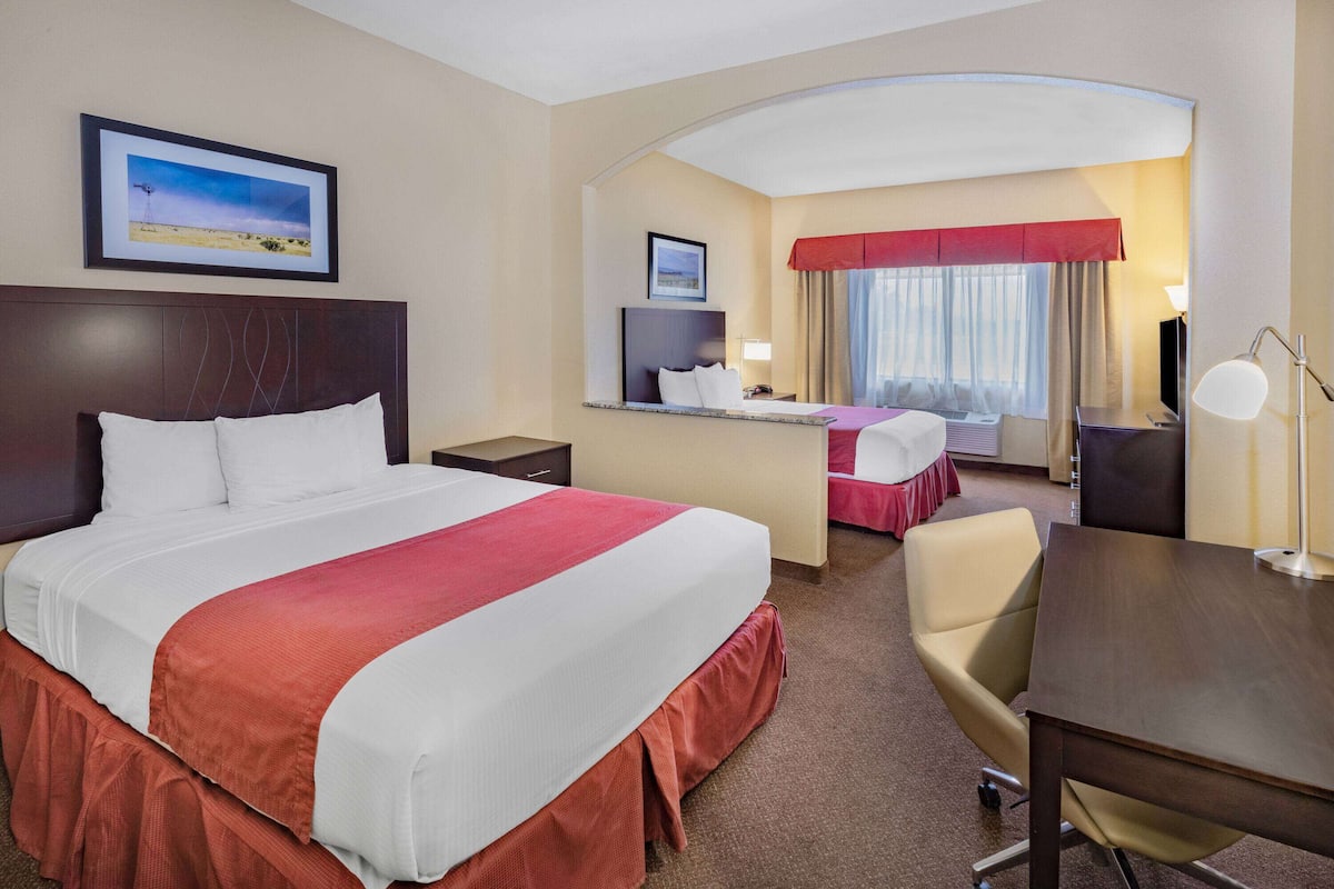 Une chambre d’hôtel avec un grand lit, un bureau, une chaise et une vue sur l’extérieur.