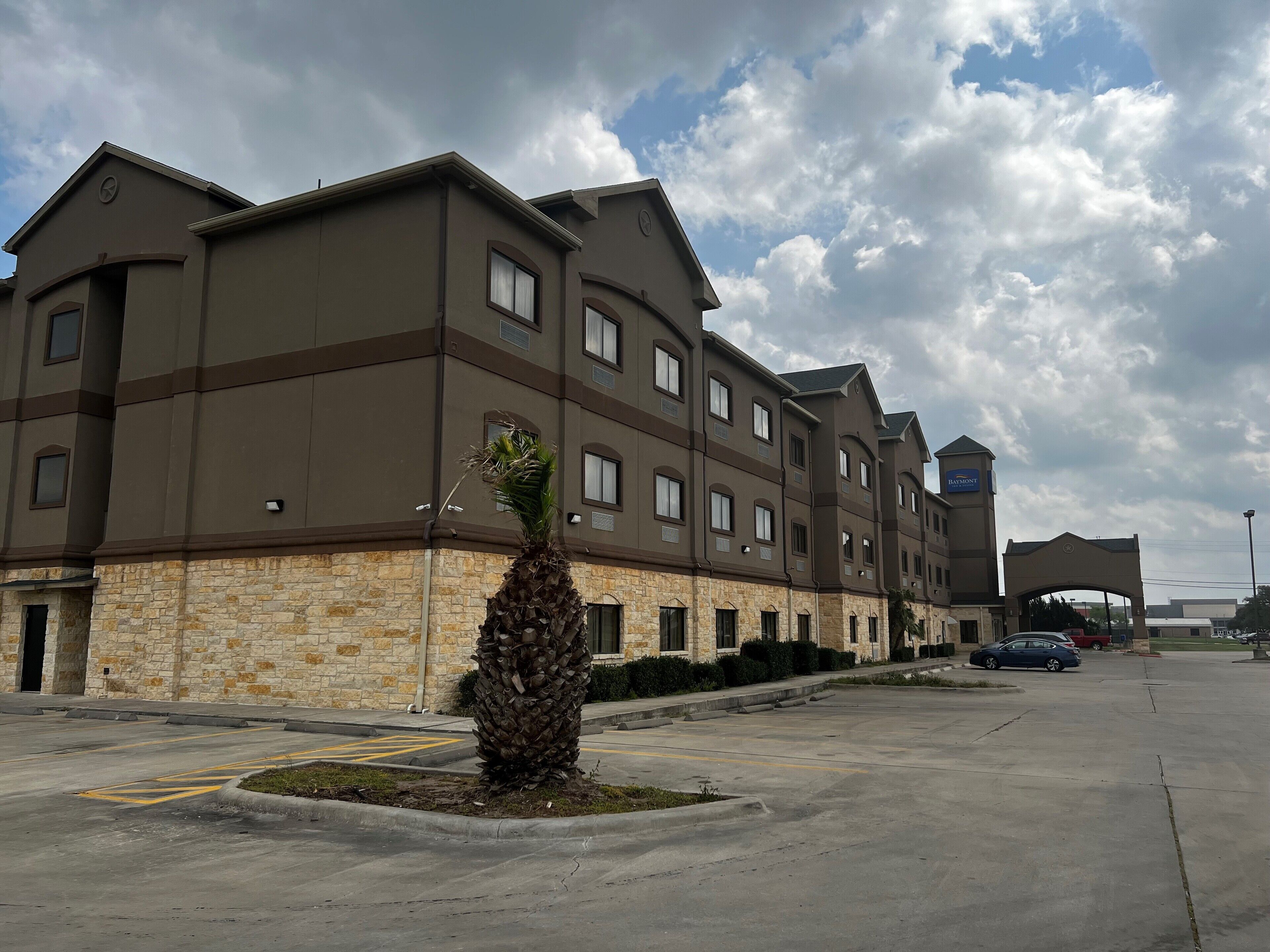 Un hôtel à plusieurs étages, doté d’une façade en pierre, de nombreuses fenêtres et d’un parking.
