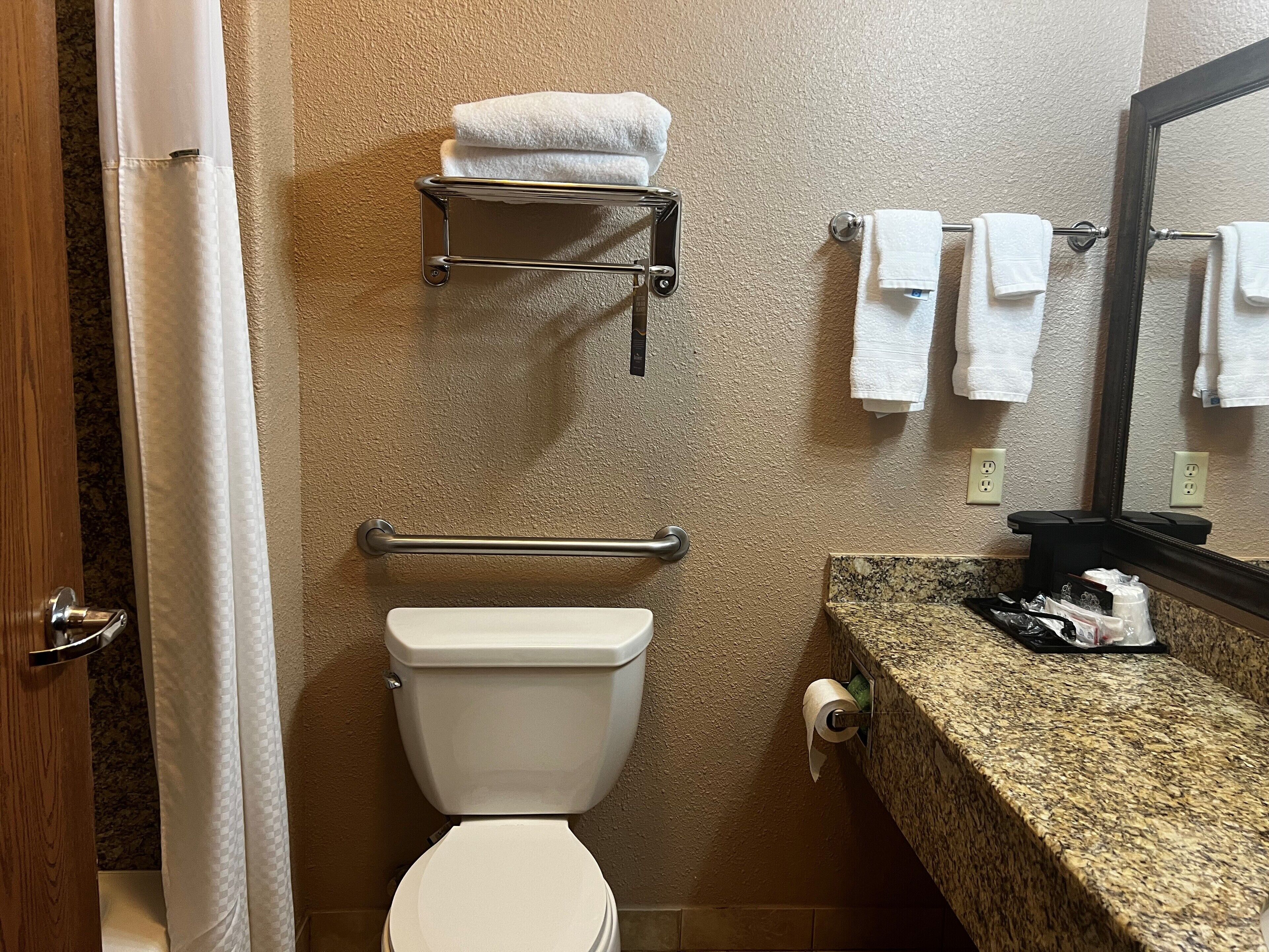 A bathroom with a toilet, towel rack, and a towel dispenser.
