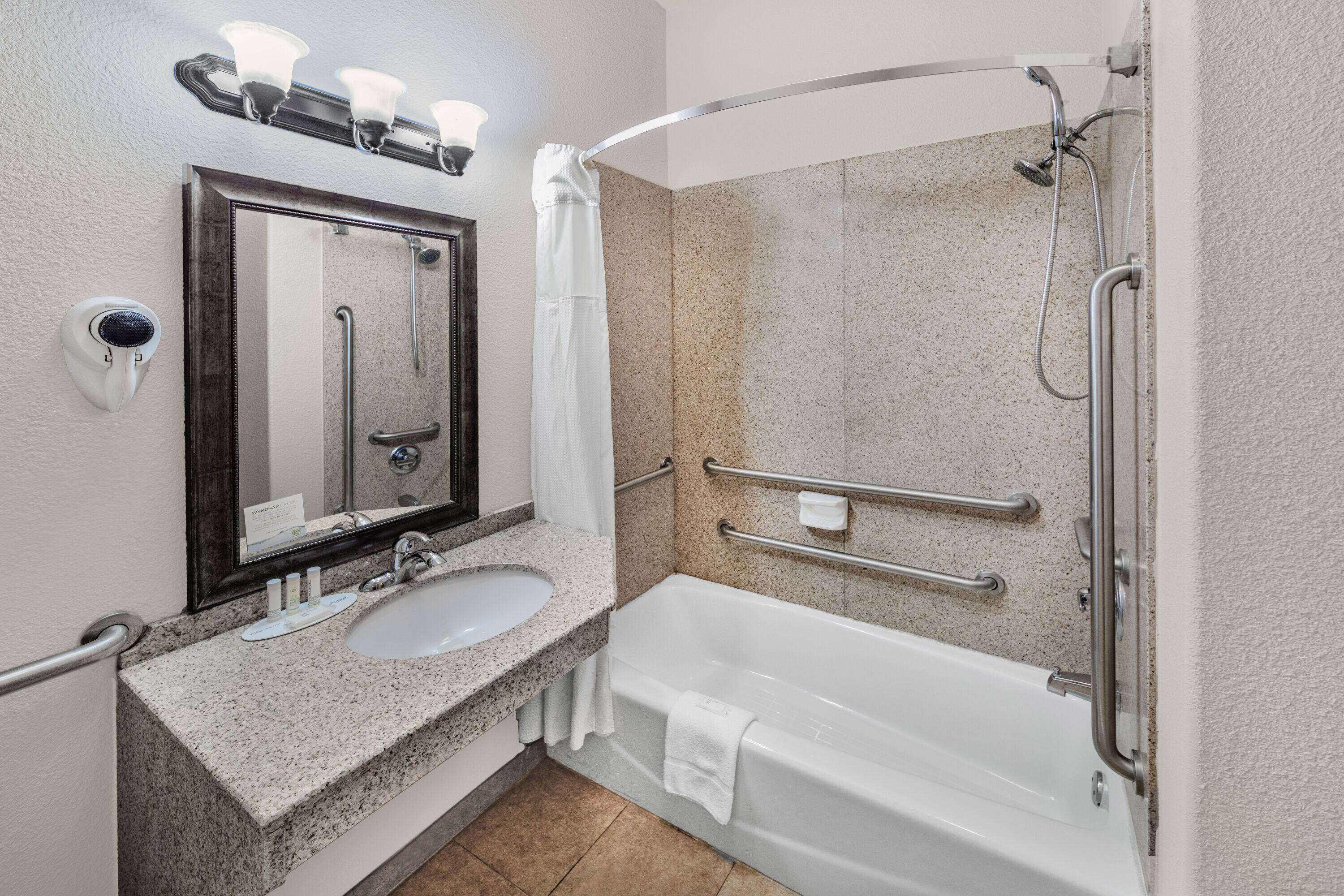 A bathroom with a sink, mirror, and bathtub.