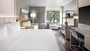 A hotel room with a large bed, a desk, a chair, a TV, and a window with curtains. - Hotel Indigo Long Island - East End by IHG (Riverhead)