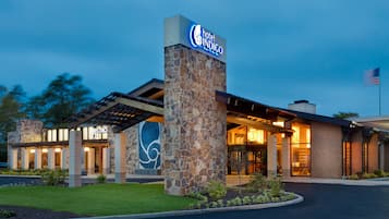 A hotel entrance with a stone pillar, a sign, and a flag.