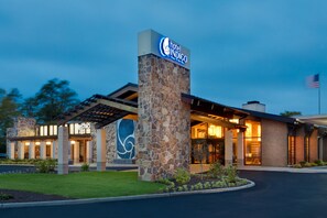 A hotel entrance with a stone pillar, a sign, and a flag. - Hotel Indigo Long Island - East End by IHG (Riverhead)
