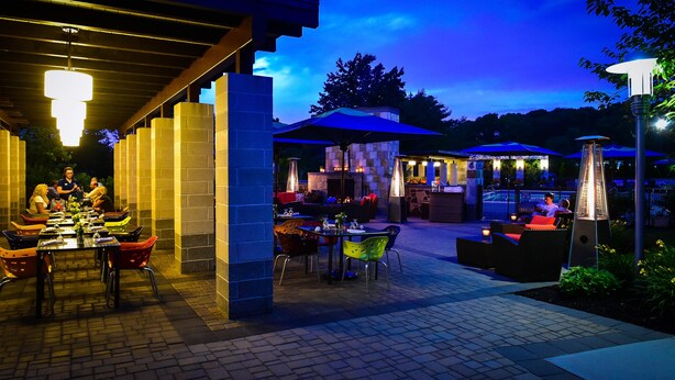 An outdoor dining area with brick walls, tables, and chairs. - Hotel Indigo Long Island - East End by IHG (Riverhead)