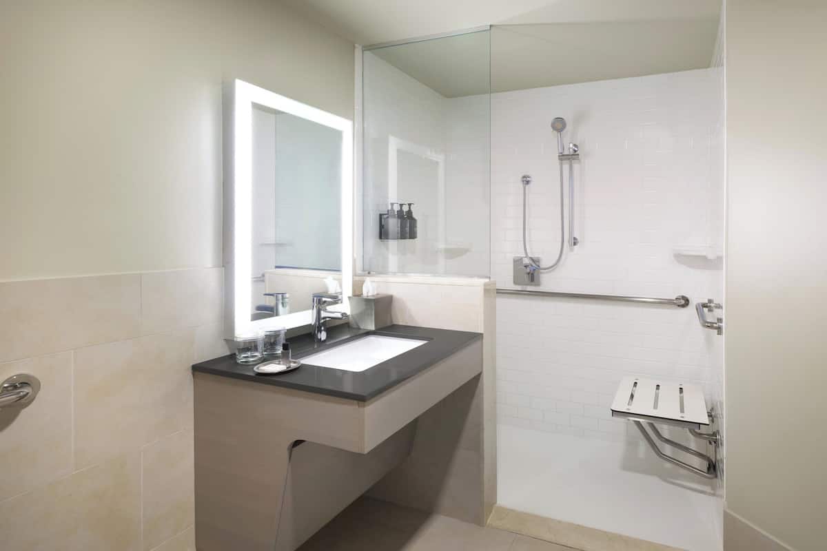 A modern bathroom with a sink, mirror, and shower.