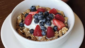 A bowl of cereal with yogurt and berries on a white plate.