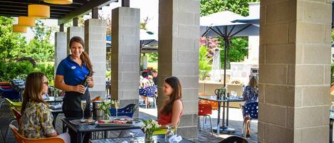Eine Außenpatio-Terrasse mit Tischen und Stühlen, einige mit Sonnenschirmen.