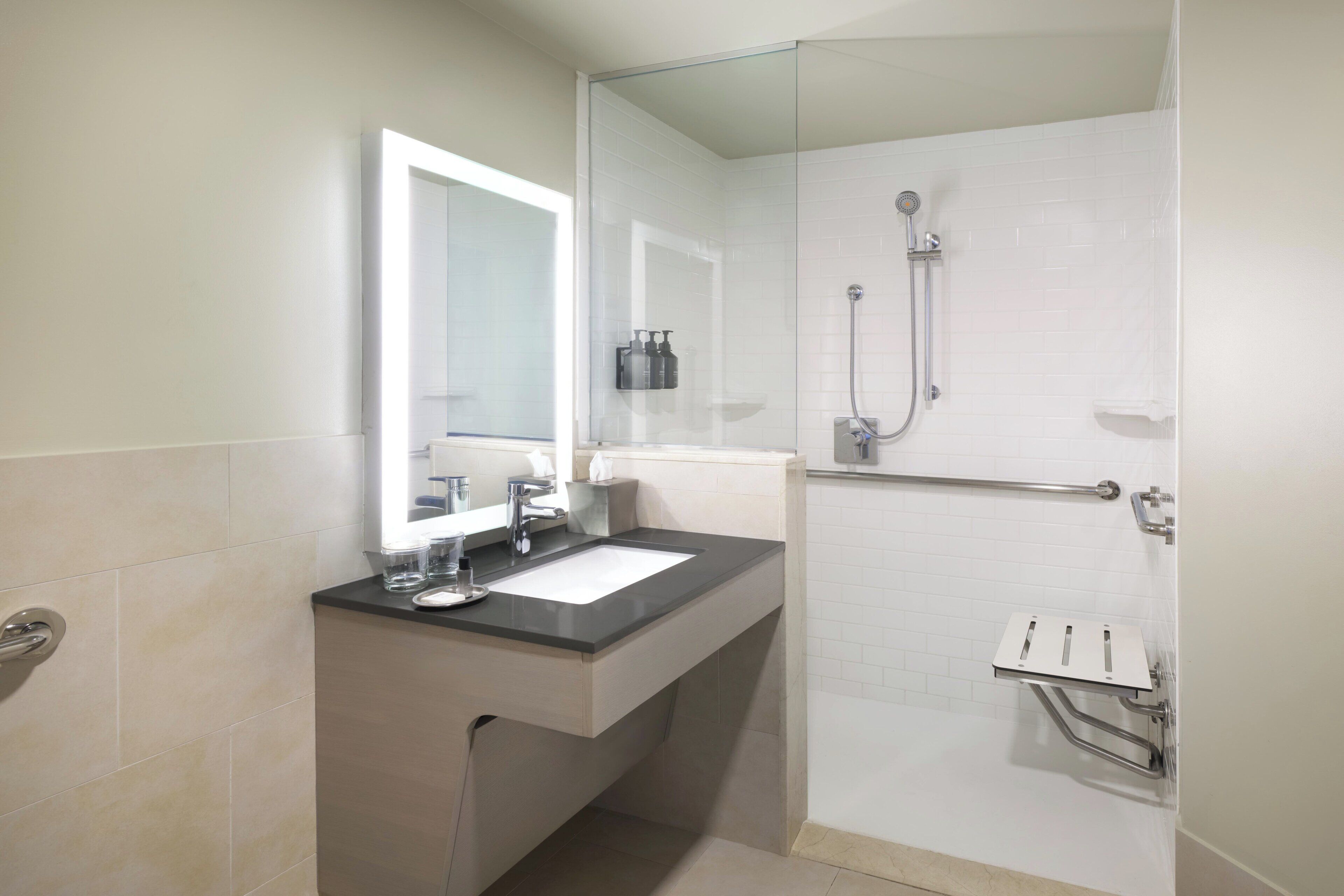A modern bathroom with a sink, mirror, and shower.