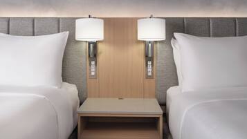 A hotel room with two beds, a wooden headboard, bedside lamps, and a small wooden table.