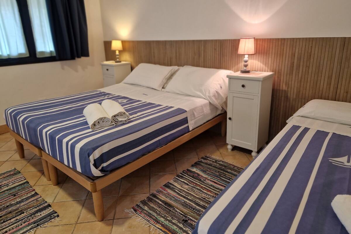 A hotel room with a bed, a nightstand, a lamp, and a window with curtains.