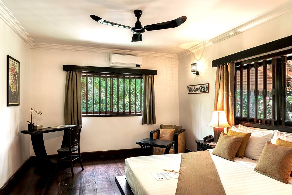 A hotel room with a bed, desk, chair, and a ceiling fan.