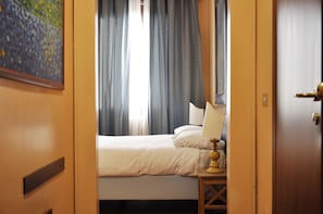 A hotel room with a bed, curtains, a lamp, and a painting on the wall. - Hotel San Guido (Milan)