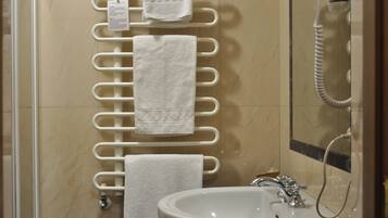 A bathroom with a white towel rack holding multiple towels, a sink with a mirror, and a telephone.