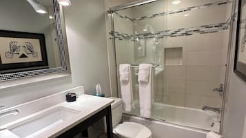 Een moderne badkamer met een douche met glazen wand, een witte wastafel en een toilet.
