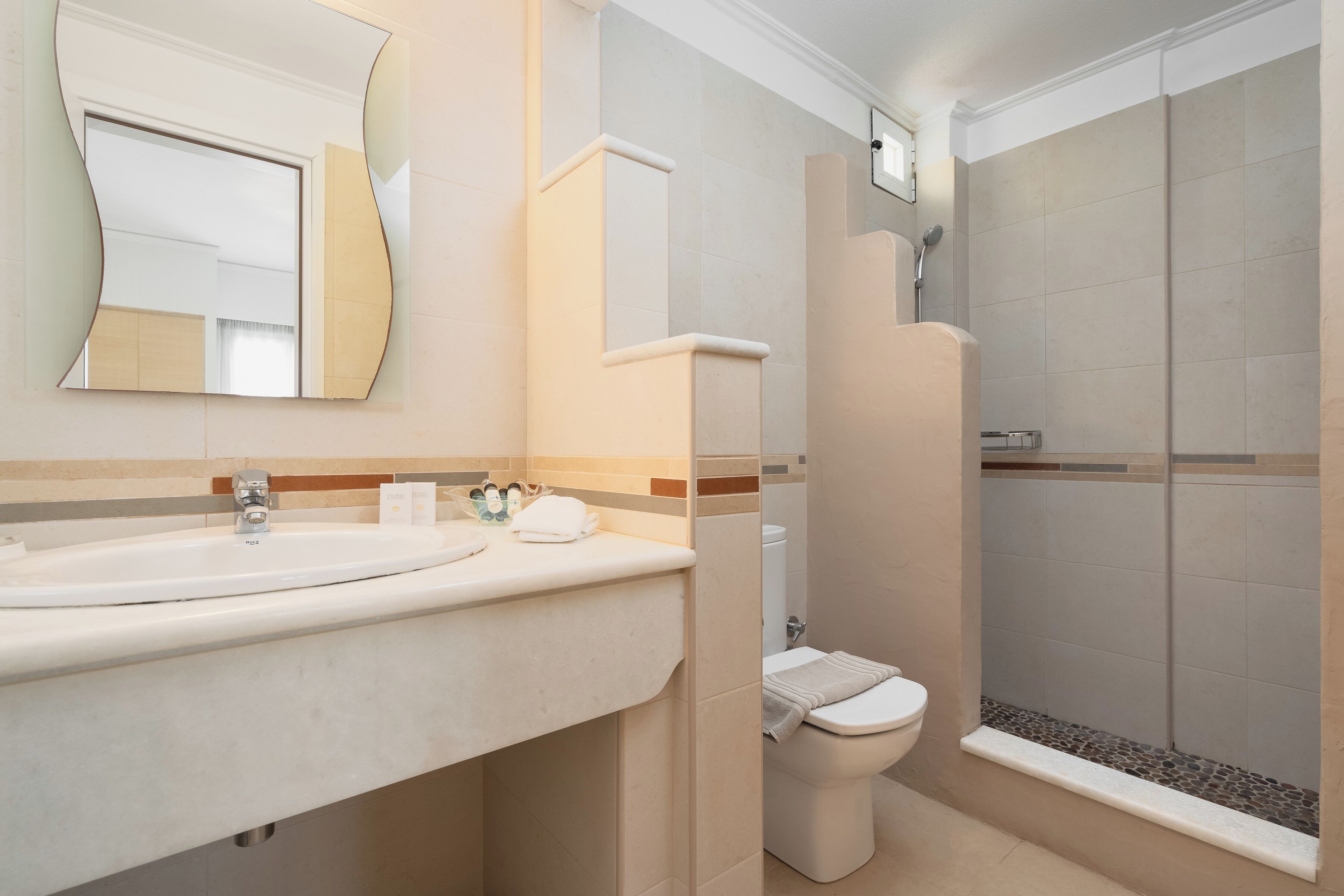 Un baño con lavamanos, inodoro y ducha.