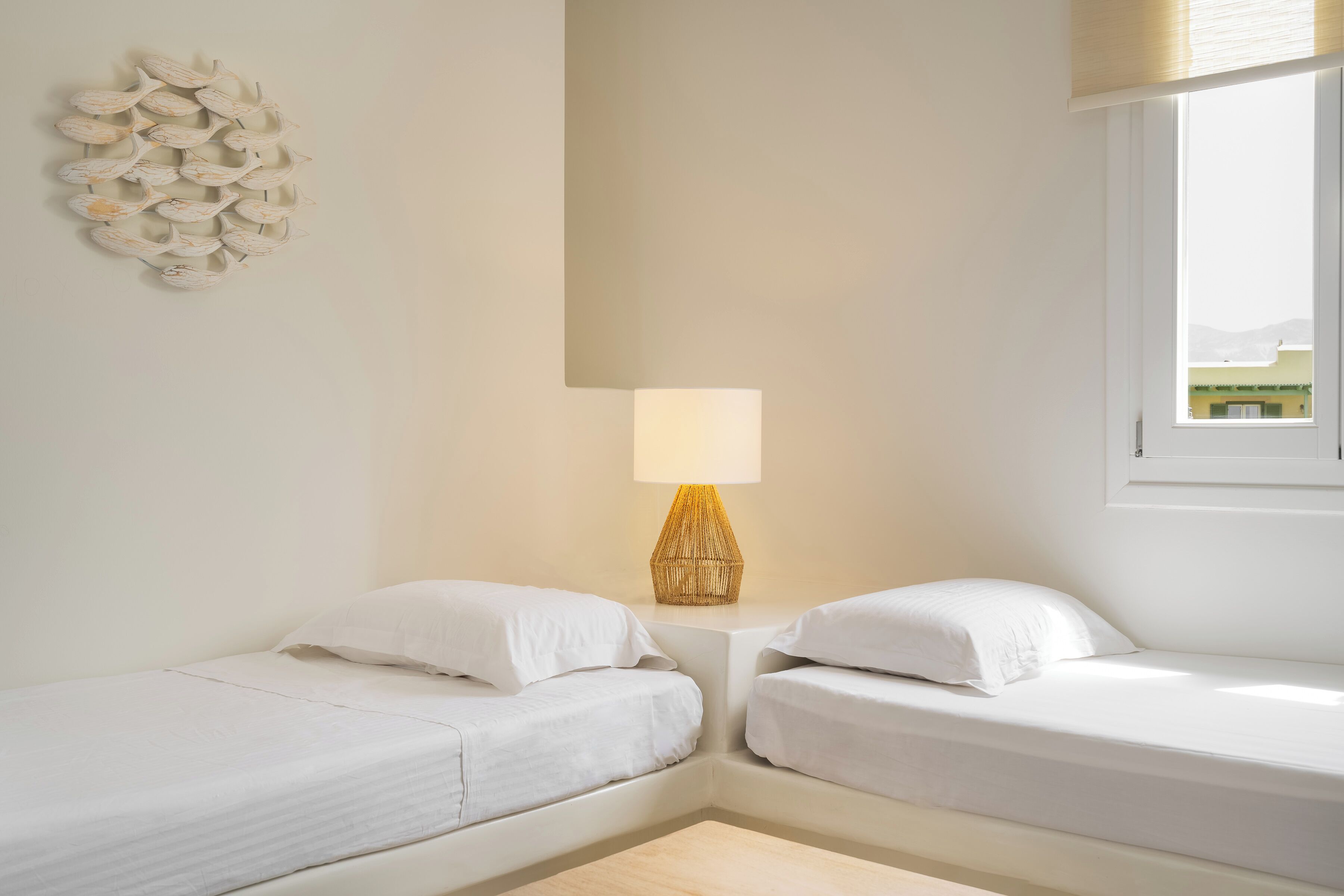 Ein kleines, sauberes Zimmer mit zwei Einzelbetten, einer Nachttischlampe und einer Wanddekoration.