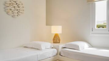 Ein kleines, sauberes Zimmer mit zwei Einzelbetten, einer Nachttischlampe und einer Wanddekoration.