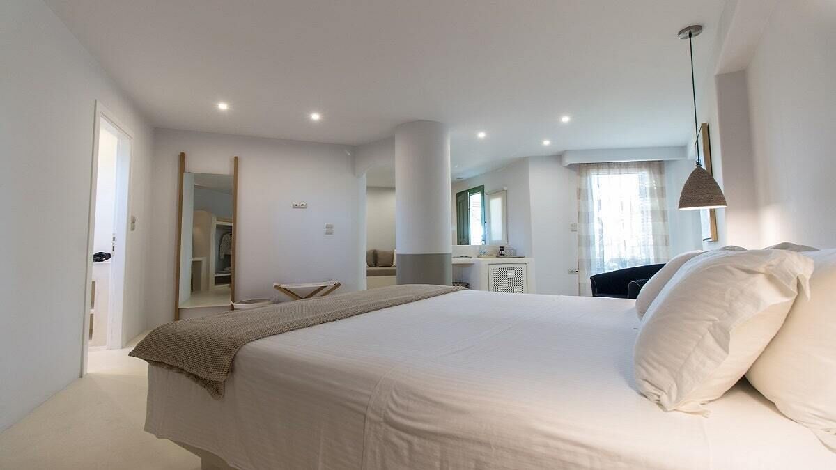 A modern bedroom with a large bed, a bedside table, a mirror, and a wardrobe.