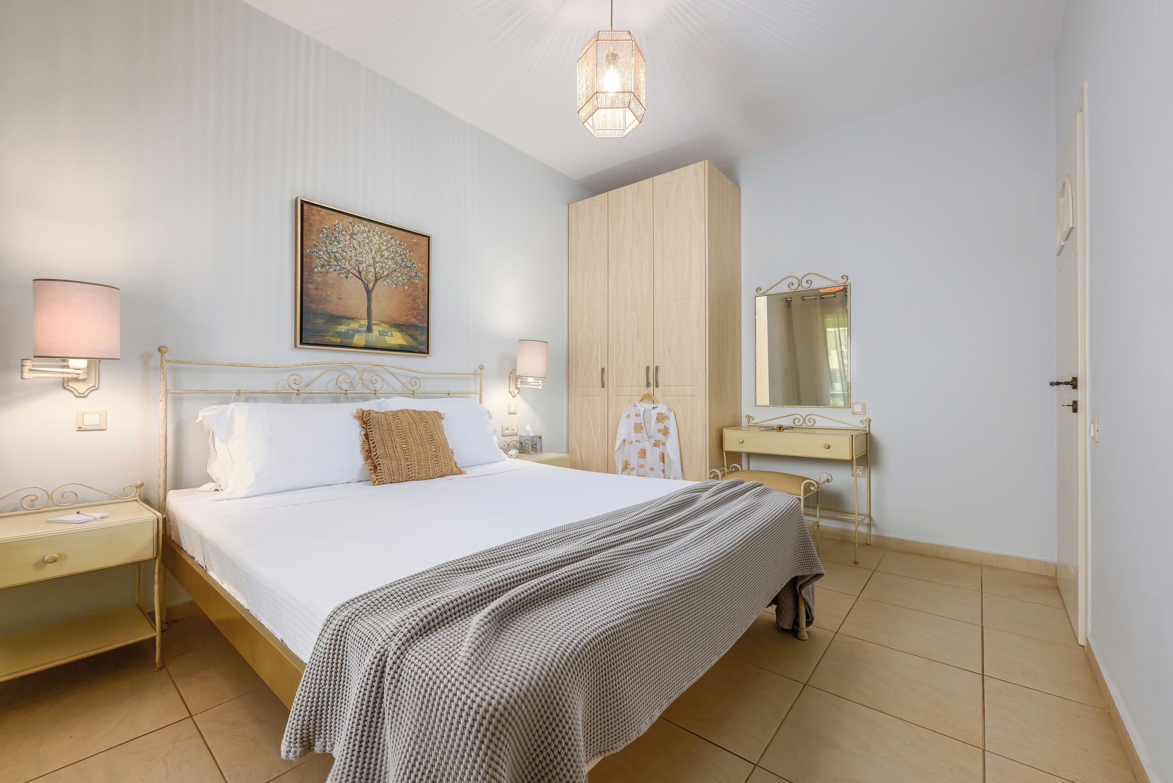 Une chambre à coucher avec un lit, des tables de chevet, une armoire, un miroir et un tableau accroché au mur.