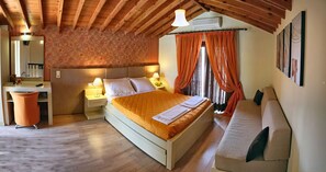A bedroom with a wooden ceiling, a bed with an orange bedspread, two bedside tables with lamps, a nightstand, and a bench. - Imerti Hotel (Lesvos)