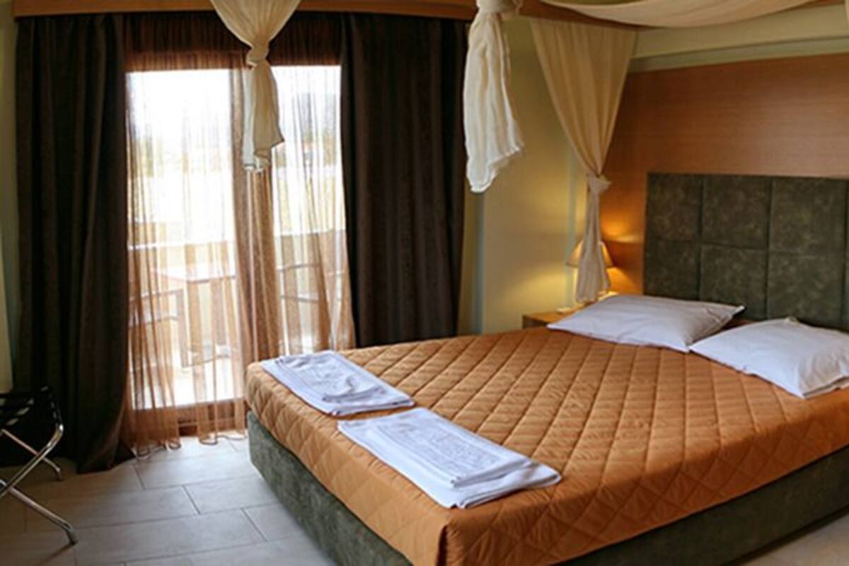 A hotel room with a large bed, a bedside table with a lamp, and a view of the bathroom through an open door.