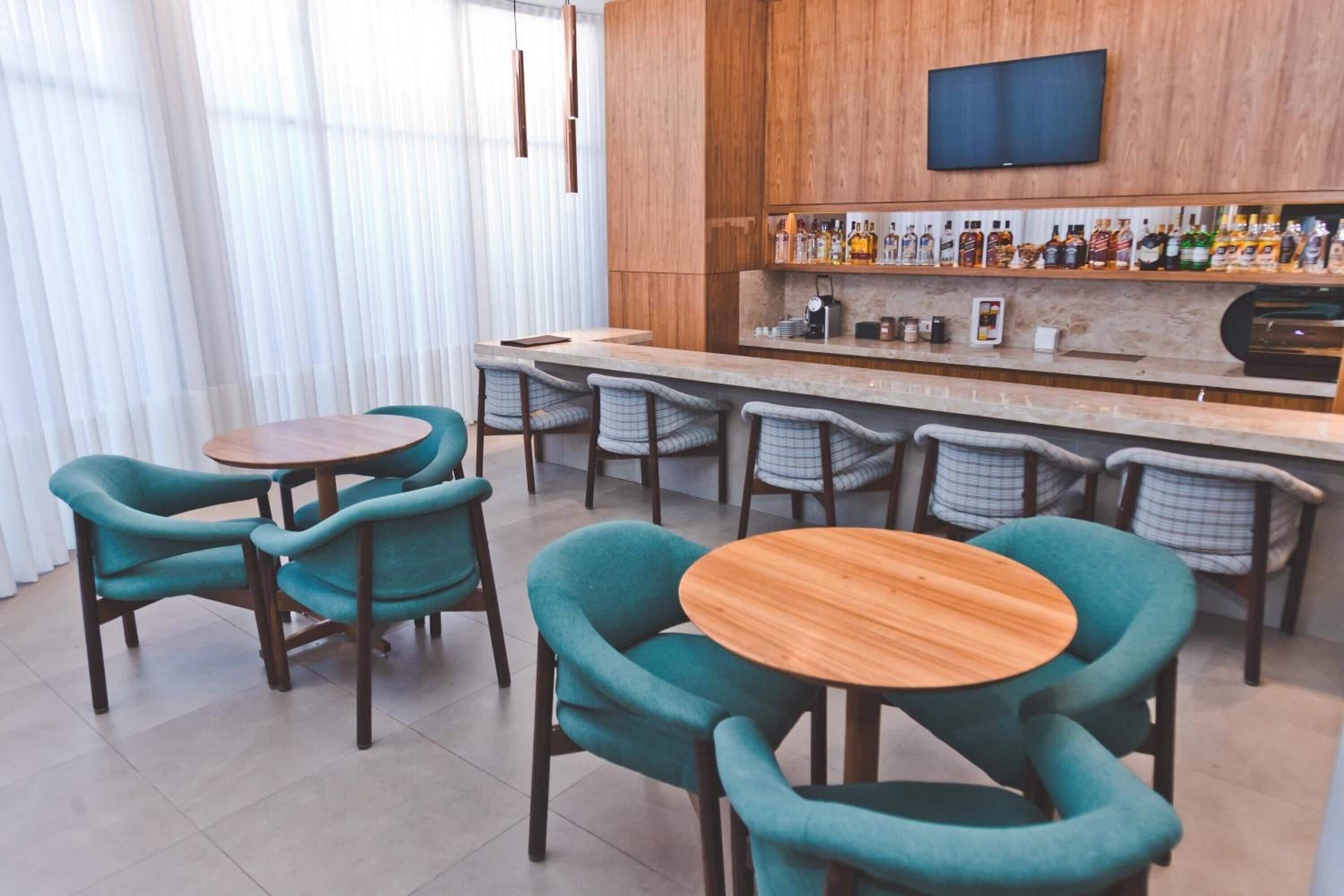 A modern bar area with wooden furniture and a variety of liquor bottles.