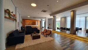 A spacious hotel lobby with a reception desk, sofas, armchairs, and a coffee table. - Transamerica Araraquara (Araraquara)