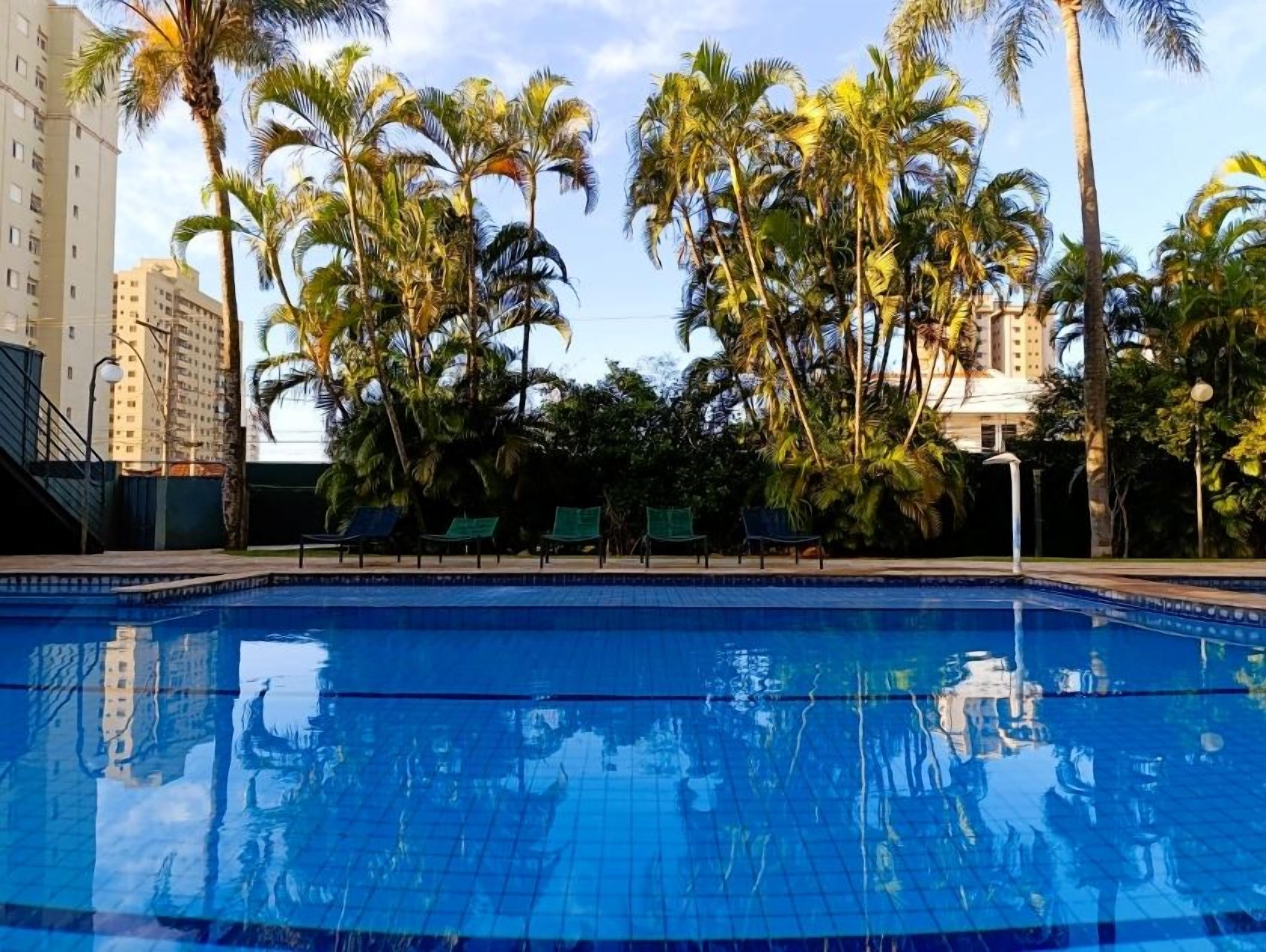 Una piscina al aire libre, sillones reclinables de piscina