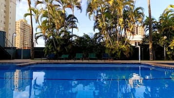 Una piscina al aire libre, sillones reclinables de piscina