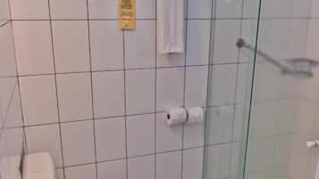 A bathroom with a toilet, a shower, and a glass-enclosed shower stall.