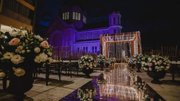 An outdoor wedding venue with a reflective water feature, floral arrangements, and a backdrop of a lit-up building. - Transamerica Araraquara (Araraquara)